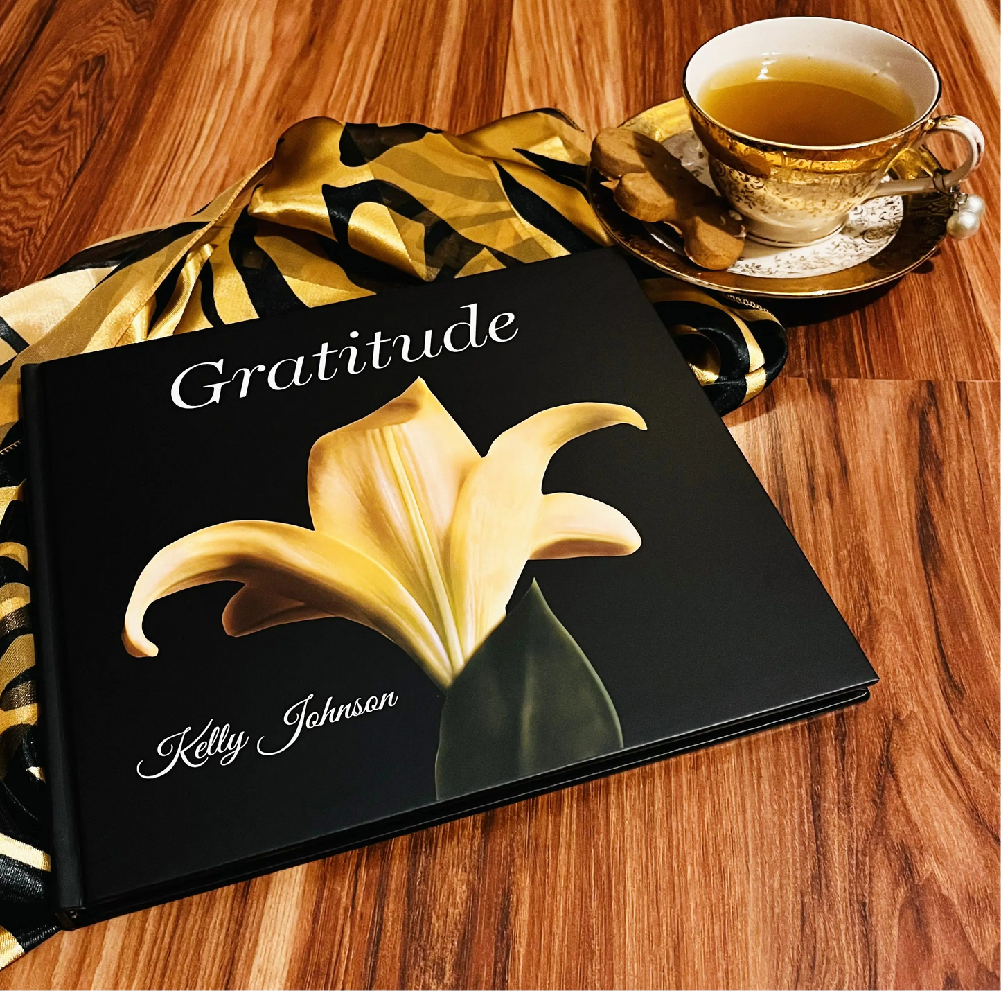 Gratitude image of a yellow lily on a wooden table with a teacup on the book cover